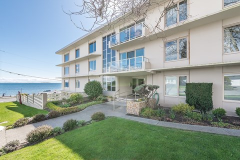 A white building with a balcony overlooking the ocean.